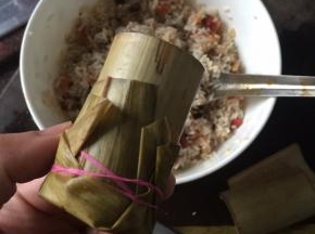 然后将米料放入竹筒里，两端用竹叶包住