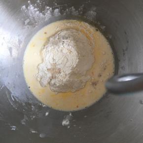 高筋面粉放入面盆内，中间挖一小孔，倒入活性干酵母粉，盐和糖对角线放置，倒入全蛋液和纯牛奶，先搅拌成絮状，再揉成团