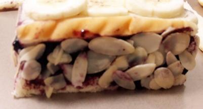 子上倒入适量杏仁片，把吐司四周沾上杏仁片。