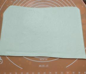 同样把白面团也擀成稍稍大一厘米的面片，然后把黑芝麻面片叠上去，卷成长条。