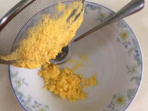 把鸡蛋黄放入面粉筛，用勺压成粉状。