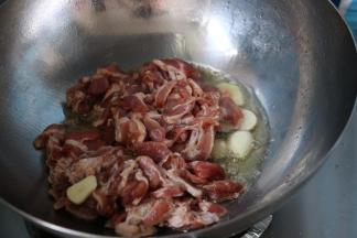 放入五花肉，反复煸炒。