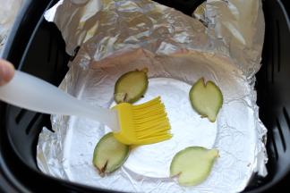 炸锅内铺上锡纸，亚光面接触食物。锡纸上刷油，铺上几片姜片。