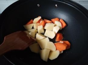 不粘加入少量色拉油，土豆和胡萝卜，翻炒2分钟