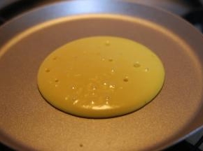 面糊会自动向周边摊开，形成圆形○，待表面冒出许多小孔且暂停时，将其翻面。