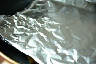 将鸡腿肉放入平坦锅。放上一张锡纸，在在上面放上一个重物(我用的的电饭煲内胆）压在鸡腿肉上。