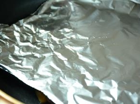 将鸡腿肉放入平坦锅。放上一张锡纸，在在上面放上一个重物(我用的的电饭煲内胆）压在鸡腿肉上。