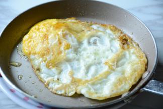 平坦锅中放入适量的菜籽油，打入鸡蛋煎至成蛋饼。