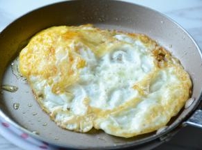 平坦锅中放入适量的菜籽油，打入鸡蛋煎至成蛋饼。