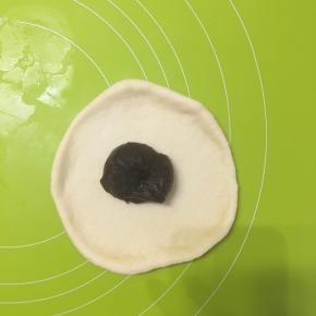 取面团擀圆后，加入适量红豆沙，包包子一样的收口包好