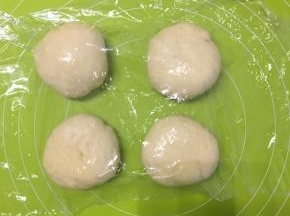 第一次发酵好的面团放在揉面垫上先揉压排出气体，分成大小相等的四份小面团，揉圆，盖上保鲜膜醒发15分钟