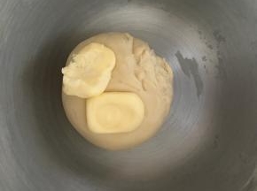 面团揉到光滑后加入软化的黄油，继续中速揉面团