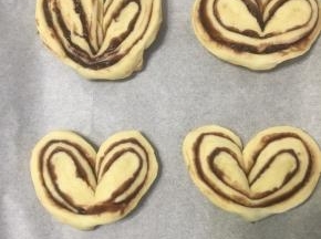 切好的面团往外两边扭开，就成心形了，盖上保鲜膜，进行第二次烤箱发酵