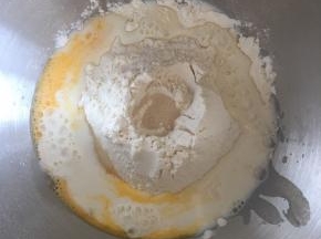 厨师机桶内先倒入牛奶，放入高筋面粉，中间挖个小孔放酵母，糖和盐对角线放，倒入全蛋液