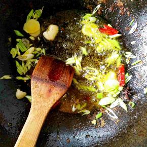 炒锅中再次倒入适量大豆油烧热之后，加入葱花，姜片，大蒜瓣，干红辣椒，大料和少量花椒粉爆锅。