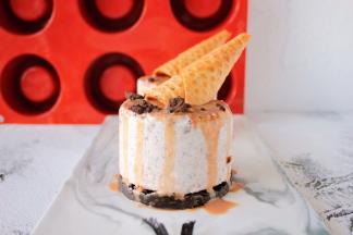 杏仁巧克力甘那许装入裱花袋，挤入凹槽内，放上甜筒蛋卷，洒上奥利奥饼干碎装饰