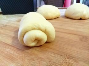 把面团反一下面，把面团擀成舌头状。将面团从上往下卷。