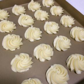 左手握裱花袋，右手出力挤，垂直与烤盘顺时针方向挤出圆形的曲奇。