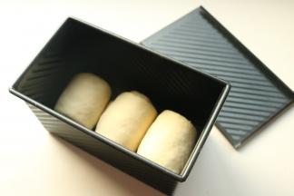 排气后分成三份，分别擀开卷起来，再擀开然后再卷起来，不要卷的太紧，排入学厨黑金刚吐司盒里。