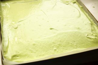 从烤盘中部注入蛋糕糊，用刮板刮平，震出大气泡。