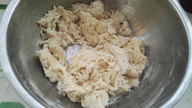 水分别倒白糖和酵母上。用筷子搅下，让白糖、酵母分别溶解下，边倒水边用筷子搅拌成面絮。