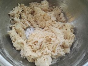 水分别倒白糖和酵母上。用筷子搅下，让白糖、酵母分别溶解下，边倒水边用筷子搅拌成面絮。