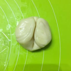 松弛好的面卷从中间压一下，向上对折，压扁，擀成圆皮