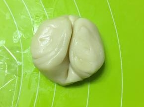 松弛好的面卷从中间压一下，向上对折，压扁，擀成圆皮