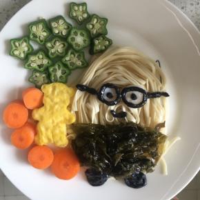 煮熟的紫菜摆成小黄人的衣服，小熊放在小黄人旁边，摆上秋葵和胡萝卜