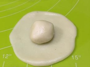 取一个水油皮压扁擀圆，包入一个油酥，像包包子一样收口