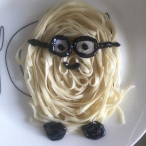 在盘子内绕圈摆出小黄人的身体，沙拉酱加入竹炭粉调匀，放在裱花袋里，蛋白皮压出两个小圆当作是小黄人的眼睛，用调好的沙拉酱裱出眼镜框和眼珠子，还有嘴，还有小黄人圆圆的脚