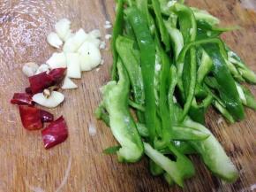 把青椒去蒂切丝，大蒜切碎，干椒辣切小段。