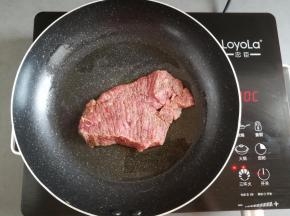 不粘锅里倒入适量的橄榄油，放入牛排