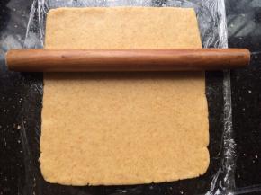 操作台上贴一张保鲜膜，把面团放上用擀面杖擀开成长方形状。