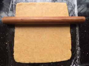 操作台上贴一张保鲜膜，把面团放上用擀面杖擀开成长方形状。