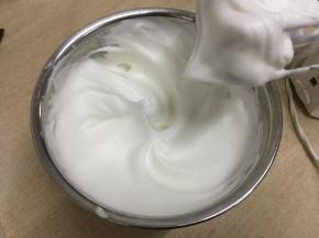 蛋白中分两次加入45克细砂糖，打发至接近干性发泡，提起打蛋头蛋白有小弯钩