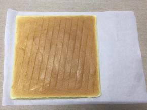 蛋糕晾凉至还有余温时，把油纸撕去，盖上一张新的油纸，然后翻面，正面朝上