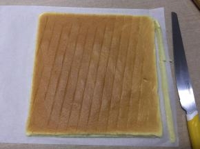 油纸短的一边是起始端，用刀往里斜切出一小条蛋糕