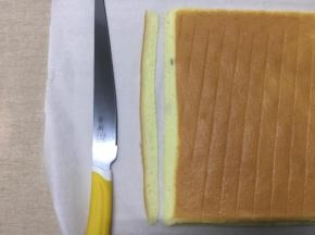 油纸长的一边是末端，用刀往外斜切出一小条蛋糕