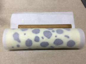 擀面杖放在起始端的油纸下面，连同油纸一起提起，向前卷，最后要往后收压，使蛋糕卷更紧实