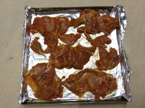 在烤盘中铺锡纸，将腌制好的鸡腿肉铺在上面