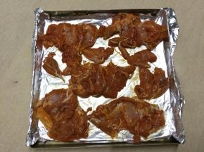 在烤盘中铺锡纸，将腌制好的鸡腿肉铺在上面