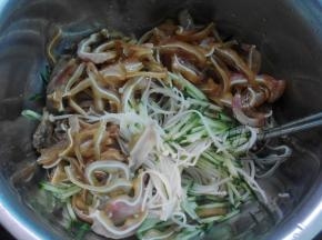 将黄瓜丝与挤干水分的金针菇放入盘中，再放入切片的卤猪耳