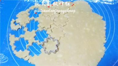 饼干模沾少许的干粉在面片上压出花型来，剩余的面团拢到一起折叠按压再次擀开重复压出花型。