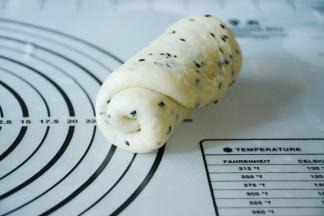 尽量将面团气泡擀出，从下往上卷起。