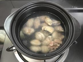 6、放入火腿肉煮开后加入洗净的花蛤。