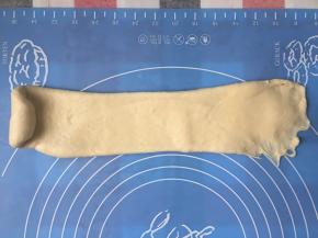 再次擀开面团，底部扒开一点，也是由上往下卷起来，后面收口捏紧，放吐司模里