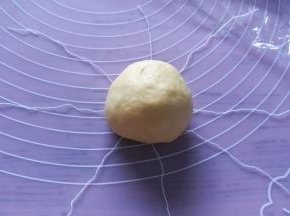 把包馅面团，放在棉线交叉的中心点，把棉线轻轻提起来，变成一绺，打个结，留出面团发酵的距离，面团发酵会膨胀。