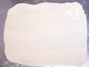 面案上撒少许手粉，把静置好的面团擀成大片状。