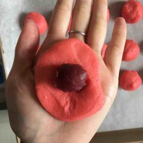 取一个面团压扁包入一点树莓麻薯